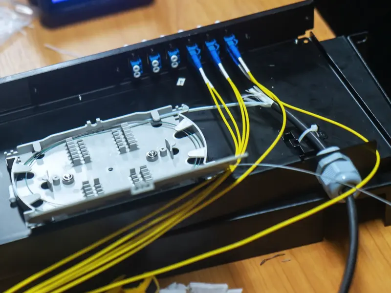 An open 1U rack LIU with a splice tray, blue LC duplex adapters and yellow pigtails